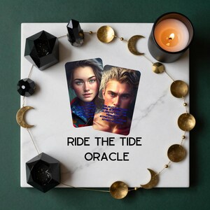 May include: Two oracle cards featuring portraits of a person with long brown hair and a person with short blonde hair, surrounded by a gold moon phase garland, black geometric crystals, and a lit candle on a white marble square with the text RIDE THE TIDE ORACLE.