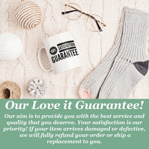 May include: A white ceramic mug with a black circle that says "100% Satisfaction Guarantee" on a white knitted surface. The mug is surrounded by a pair of gold-rimmed glasses, a ball of twine, a small pine cone, and a pair of gray socks. The text "Our Love it Guarantee!" is written in a green box below the image.