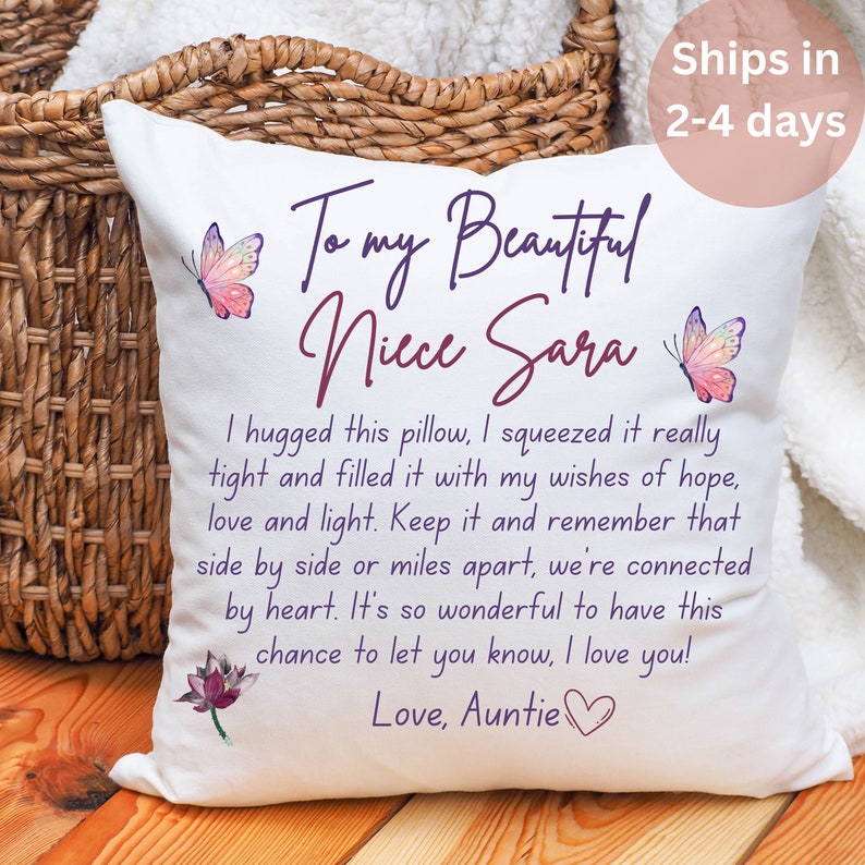 May include: White square cushion with text, butterflies, and a lotus flower. The cushion reads "To my Beautiful Niece Sara" and includes a heartfelt message from "Love, Auntie". The cushion is placed near a woven basket.