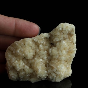 May include: A cluster of white calcite crystals with a rough, textured surface. The crystals are clustered together in a natural formation, creating a unique and interesting shape.