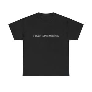 May include: Black t-shirt with the text "A STANLEY KUBRICK PRODUCTION" printed in white across the chest. The shirt has a crew neck and short sleeves. The fabric appears to be a soft cotton blend.