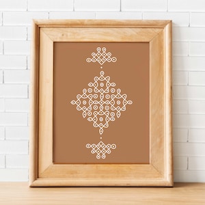 May include: A framed print featuring a symmetrical white geometric design on a brown background. The artwork is enclosed in a light brown wooden frame, set against a white brick wall. The design is composed of interconnected dots and lines.