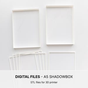 May include: Two white rectangular shadowbox frames and several thin white frame components arranged on a flat surface. The text DIGITAL FILES - A5 SHADOWBOX STL files for 3D printer is printed in black at the bottom of the image.