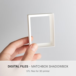 May include: A white rectangular frame with a hollow center, designed as a matchbox shadowbox. The text at the bottom reads: DIGITAL FILES - MATCHBOX SHADOWBOX. STL files for 3D printer. This object is a digital file for 3D printing.