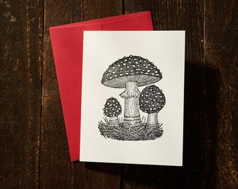 Ilustración linograbada de tarjeta de setas Amanita sobre papel de algodón con sobre rojo