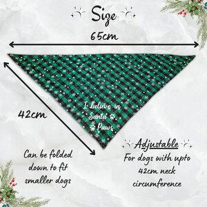 May include: Green and black plaid dog bandana with white snowflake accents. The bandana is triangular, measuring 65cm wide and 42cm long. Text reads "I believe in Santa Paws." Adjustable for dogs with up to a 16.5-inch neck.