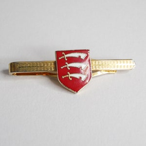 May include: Gold tie clip with a red enamel shield featuring three white swords.