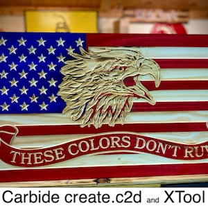 May include: A wooden American flag with a carved eagle and the text "These Colors Don't Run".