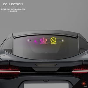 May include: Rear window/glass holder collection. The image shows a car's rear window with three illuminated decals. The decals include a crown, a symbol with a crossed-out cigarette, and other graphic elements. The car is dark gray.