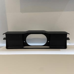 May include: Black metal frame with a circular cutout in the center. The frame has two rectangular sections on either side of the cutout.