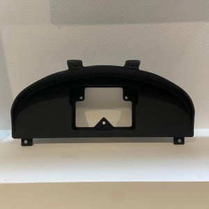 May include: Black plastic automotive gauge cluster housing with a rectangular cutout for the gauges.