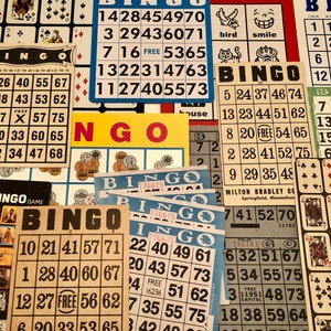 May include: A close-up of several bingo cards with numbers and the word "FREE" in the center of each card. The cards are on a table with other bingo cards and a yellow and red sign that says "Bingo".