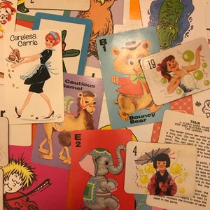 May include: A collection of colorful cards featuring various animals and characters. The cards include a camel, an elephant, a bear, a clown, an owl, a crocodile, and a girl with balloons. The cards are numbered and have a letter and a word on them. The cards are part of a game called "A Train for Two Players - One Flash Card Game".