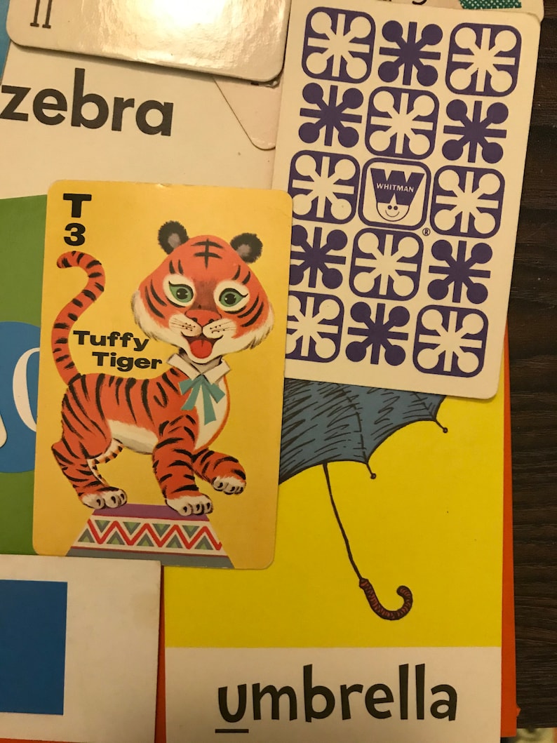 May include: A yellow card with a cartoon tiger on it. The tiger is orange and black with a blue bow tie. The card says "Tuffy Tiger" and "T 3".