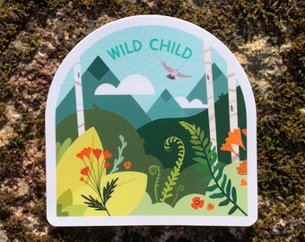 Könnte beinhalten: Ein gestanzter Aufkleber mit einem Naturmotiv. Der Aufkleber zeigt eine Landschaft mit Bergen, Bäumen und Blumen, mit den Worten "WILD CHILD" oben. Ein Vogel fliegt am Himmel. Der Aufkleber befindet sich auf einer moosigen Oberfläche.