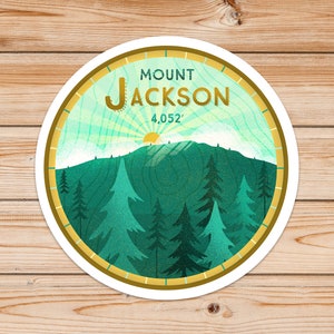 May include: A round sticker with a green mountain scene and the text "MOUNT JACKSON 4,052'" in gold lettering. The sticker has a gold border and a white background.