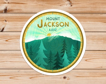 May include: A round sticker with a green mountain scene and the text "MOUNT JACKSON 4,052'" in gold lettering. The sticker has a gold border and a white background.