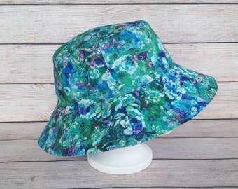 May include: A green and blue bucket hat with a floral print. The hat is made of a soft, lightweight fabric and has a wide brim.