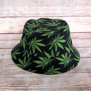 May include: A black bucket hat with a green marijuana leaf pattern.