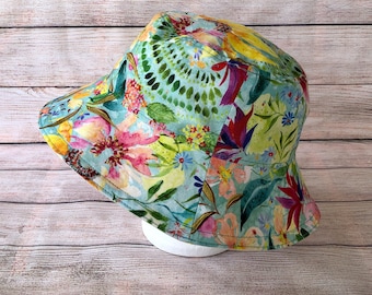 May include: A blue and green bucket hat with a floral print. The hat has a wide brim and is made of a lightweight fabric.