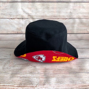 May include: Black bucket hat with a red and yellow Kansas City Chiefs logo print on the brim.