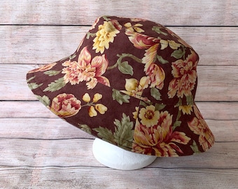 May include: A brown floral bucket hat with a wide brim. The hat is made of a soft, cotton fabric and features a variety of colorful flowers.