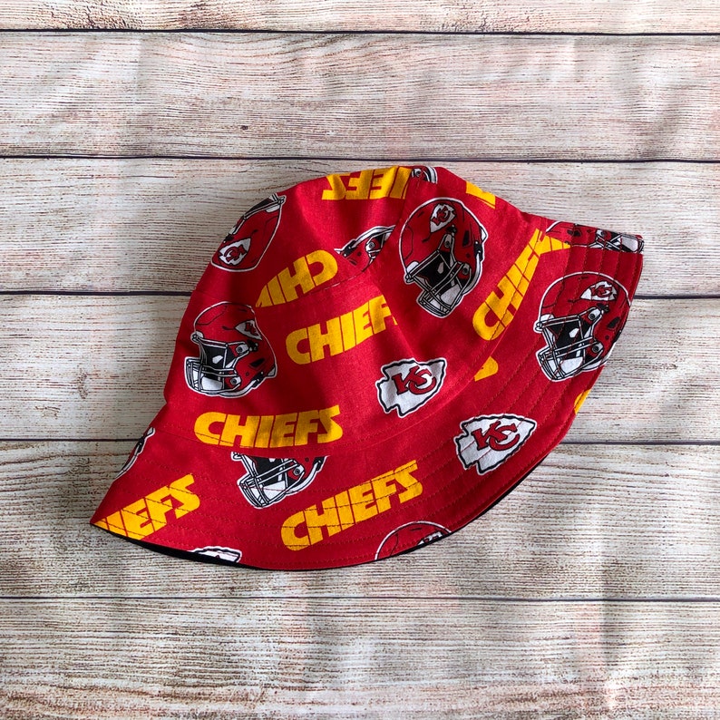 May include: Red and yellow bucket hat with the Kansas City Chiefs logo and the word "Chiefs" repeated on the fabric.