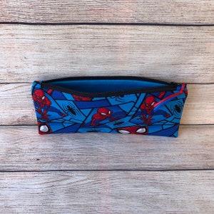 Puede incluir: Una bolsa azul con cremallera con un patr&oacute;n repetido de personajes de Spiderman y telara&ntilde;as. La bolsa est&aacute; abierta y el forro interior es azul.