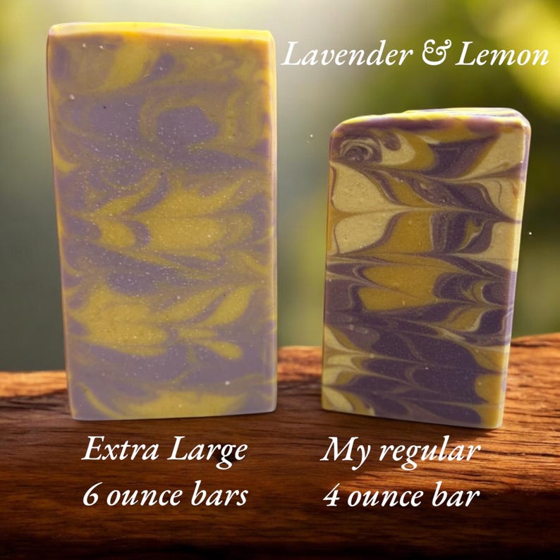 May include: Two rectangular bars of Lavender & Lemon soap with a marbled purple and yellow pattern. The larger bar is labeled as an Extra Large 6 ounce bar, while the smaller bar is labeled as My regular 4 ounce bar, indicating their respective sizes.