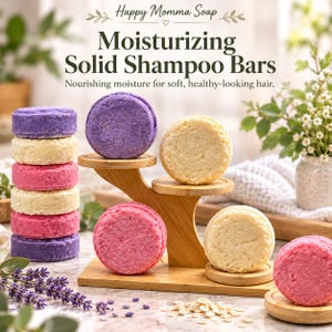 May include: Round solid shampoo bars in purple, cream, and pink colors arranged on a tiered wooden stand and in a stack. The text reads Happy Momma Soap, Moisturizing Solid Shampoo Bars, Nourishing moisture for soft, healthy-looking hair.