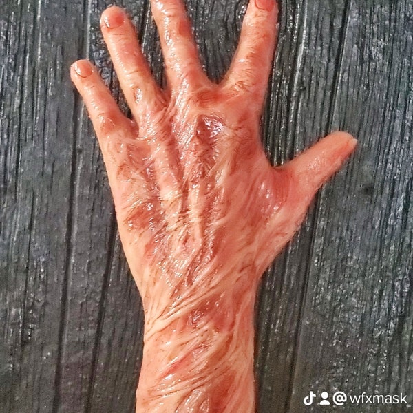May include: A prosthetic left hand glove in a realistic flesh tone, with visible veins and skin texture. The text "Left Hand Glove" is displayed in green. The glove is set against a dark, textured background.