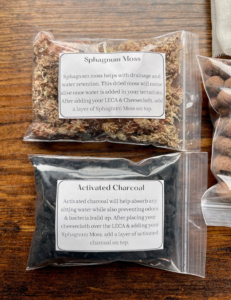 May include: Two clear plastic bags containing terrarium supplies. One bag holds dried Sphagnum Moss, with text describing its use for drainage and water retention. The other bag contains Activated Charcoal, with text explaining its function in absorbing water and preventing odors.