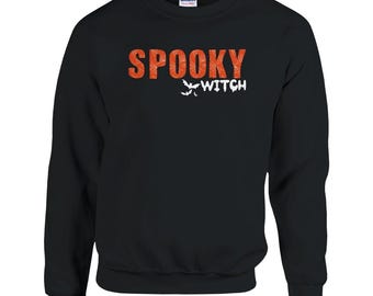 May include: Black sweatshirt with the words "SPOOKY WITCH" in orange and white. The word "SPOOKY" has a distressed texture. Below the word "SPOOKY" are three white bat silhouettes, and the word "WITCH" in white.