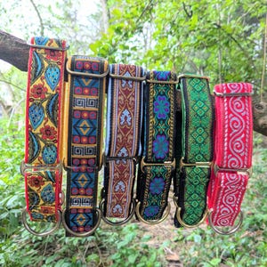 May include: Six adjustable fabric collars with metal hardware, each featuring a distinct woven pattern. The designs include yellow floral, geometric blue and gold, ornate red and cream, dark floral, green diamond, and red with white swirl motifs.