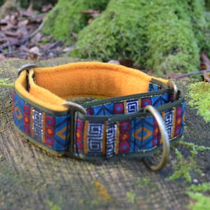May include: A dog collar featuring a blue fabric strap with a repeating geometric pattern in red, yellow, and silver, lined with a soft mustard yellow fleece material, and equipped with antique brass-toned metal hardware including a large D-ring.