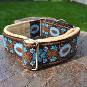 May include: A brown and black dog collar with a floral pattern in shades of blue, white, and brown. The collar is lined with a soft, beige fabric.