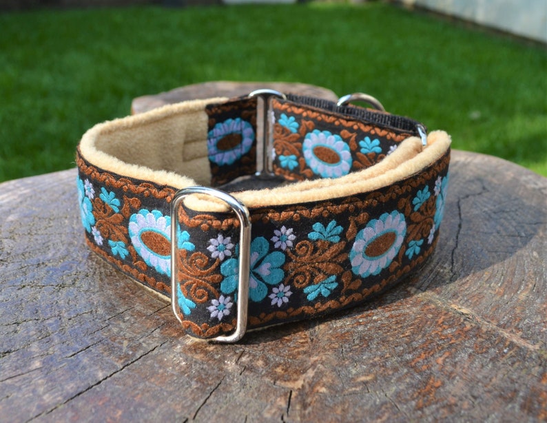 May include: A brown and black dog collar with a floral pattern in shades of blue, white, and brown. The collar is lined with a soft, beige fabric.