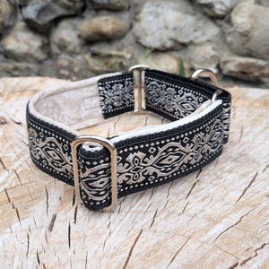 May include: A black and beige patterned collar featuring a repeating geometric design. The collar is constructed with a durable fabric strap, a light-colored interior lining, and polished silver-toned metal hardware including a rectangular slide.
