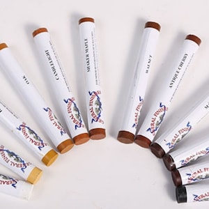 May include: A set of 12 wood stain markers in various colors, including white, pine, honey maple, oak, candlelight, sugar maple, walnut, antique cherry, mahogany, brown mahogany, dark walnut, and black. The markers are labeled with the name of the stain color and the brand "General Finishes".