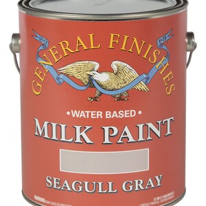 May include: A 1-gallon can of General Finishes Milk Paint in Seagull Gray. The can is red with a white eagle and blue ribbon logo. The text "WATER BASED" and "MILK PAINT" are printed in black. The can has a warning label that says "MAY CAUSE EYE IRRITATION."