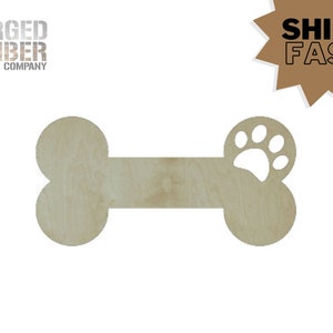 May include: A wooden dog bone-shaped cutout with a paw print design on one end. The cutout is made of light-colored wood and features the text "FORGED TIMBER COMPANY". The image also includes a brown starburst with the text "SHIPS FAST".