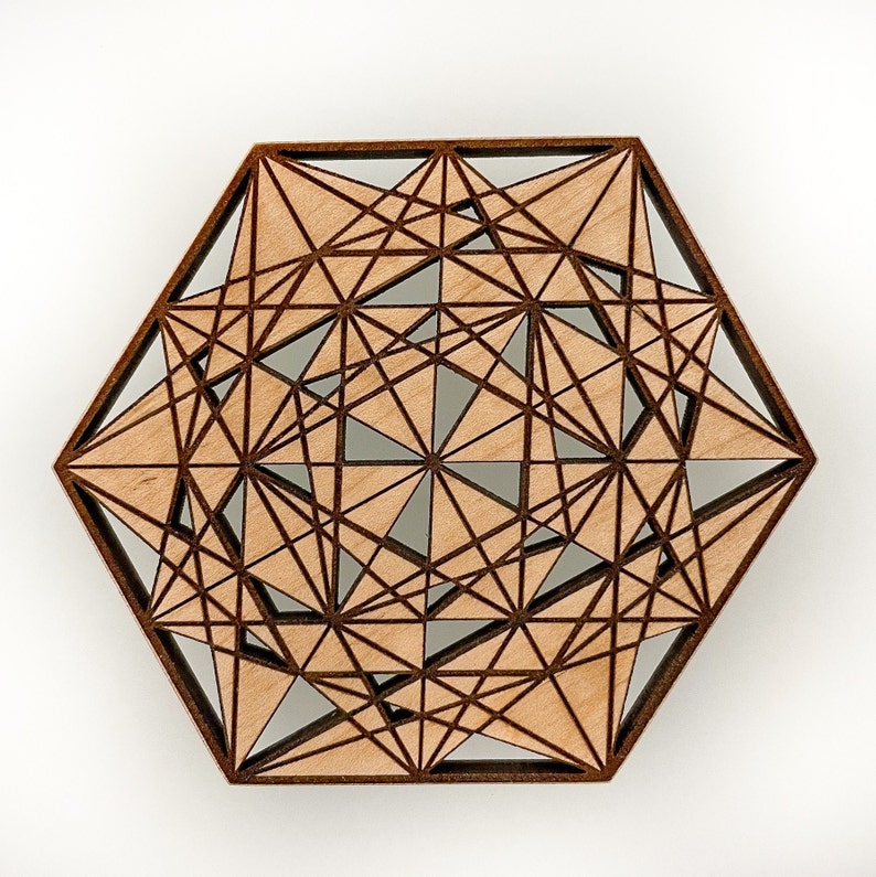 May include: A geometric wooden coaster with a hexagonal shape. The coaster features a complex design of intersecting lines and triangles, with a light brown wood color and a darker brown border.