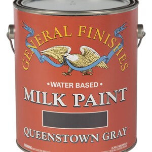 May include: A red, white, and blue can of General Finishes Milk Paint in the color Queenstown Gray. The can is labeled with the company logo and the text "Water Based" and "Milk Paint".
