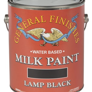 May include: A 1-gallon can of General Finishes Milk Paint in Lamp Black. The can is red with a white eagle and ribbon design. The text "General Finishes" is in a white script font. The text "Milk Paint" is in a black sans-serif font. The text "Lamp Black" is in a black sans-serif font. The text "Water Based" is in a black sans-serif font. The text "Since 1928" is in a white sans-serif font. The text "Warning: May Cause Eye Irritation" is in a black sans-serif font.