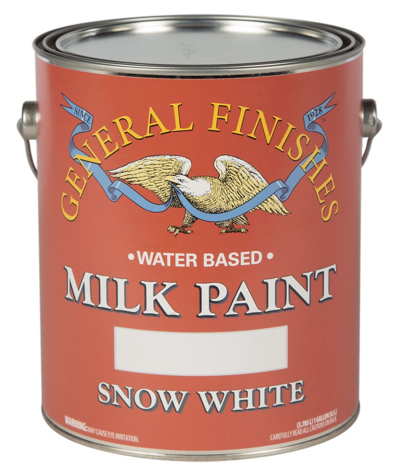 May include: A red can of General Finishes Milk Paint in the color Snow White. The can is labeled with the company logo, a bald eagle with a blue ribbon, and the text "Water Based".