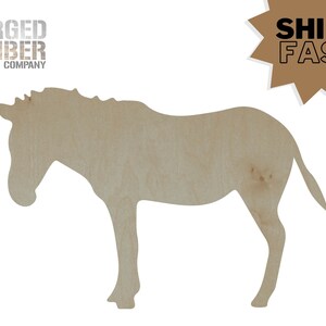 May include: A wooden cutout of a zebra in a light brown color. The zebra is standing with its head down and tail up. The text "FORGED TIMBER COMPANY" is at the top left. The text "SHIPS FAST" is in a brown starburst.