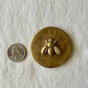 May include: A gold round trinket box with a raised bee design on the lid.