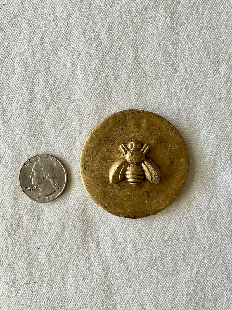 May include: A gold round trinket box with a raised bee design on the lid.