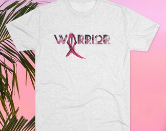 May include: A gray t-shirt with a pink ribbon and the word "WARRIOR" printed on it. The ribbon and text are stylized with a paint splatter effect.