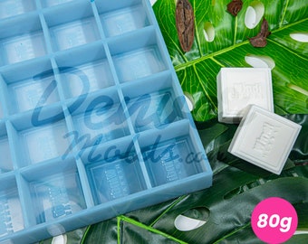 May include: A light blue silicone mould with 16 square cavities. The mould is designed to create 80g soap bars. Two white soap bars are shown next to the mould.